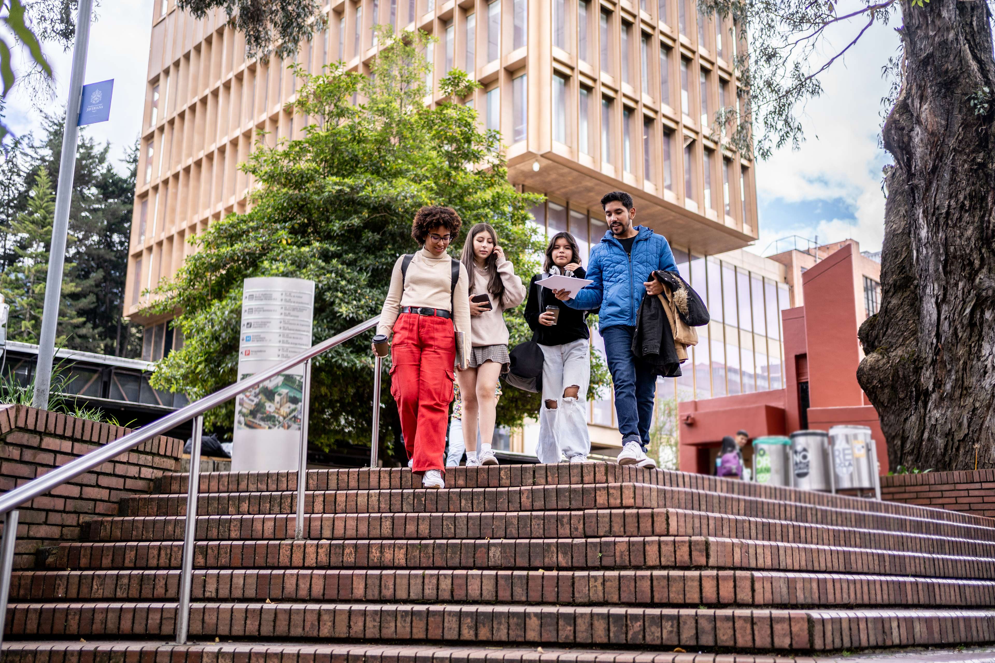 three female students and one male student walking down university staircase towards camera